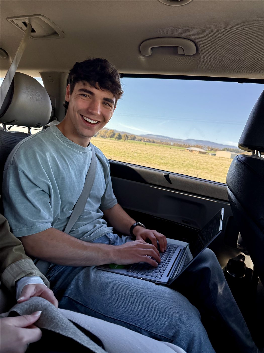 Henri working on a laptop during a car trip